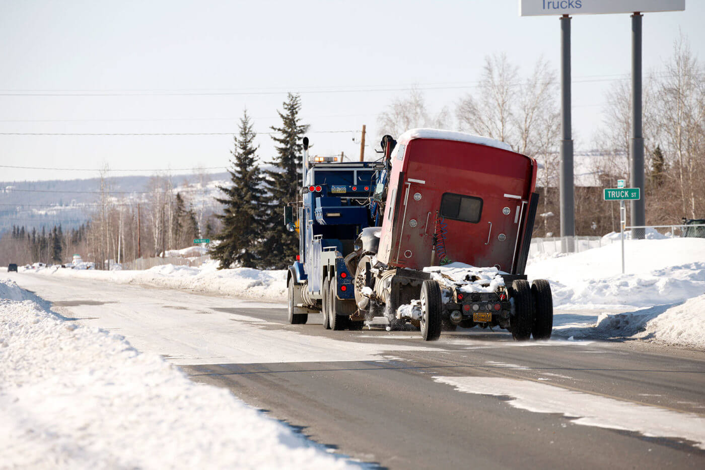 Ben's Towing truck tows semi truck down snowy highway.